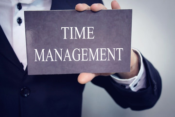 Time management - Businessman holding chalkboard with text.