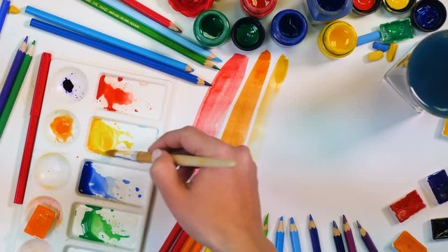 Colorful background. Artist hand drawning rainbow. Artist desk from above. 4K.
