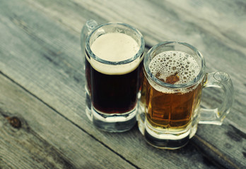Two glasses of light and dark beer on an old wooden surface