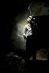 Portrait of a gangster dressed in retro suit with hat, smoking cigar and holding gun in hands....