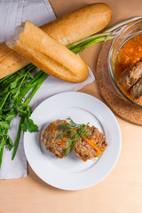 Rissole of pork served on a white plate with white wheat bread and herbs - dill, green onion, parsley around the plate.