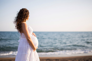 Young pregnant woman walking on the beach 