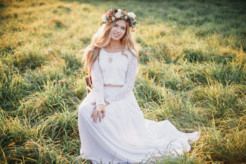 Beautiful blond bride with a wreath on his head. Outdoors.
