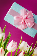 bouquet of white and pink tulips and a gift on a colored background