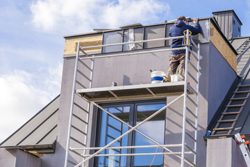 Naklejka premium Roofer assembles sheet metal on the roof. Roofers on the roof.