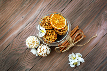 Decorative balls and dried orange in glass ball with cinnamon on a wooden table with a variety of beautiful items.