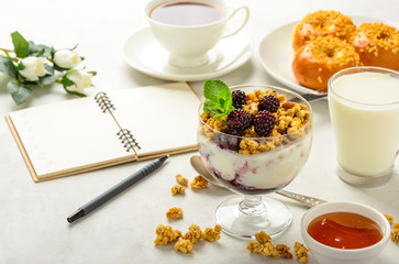 Delicious and healthy breakfast of granola, buns brioche, honey and black tea on a light background . Soft focus.