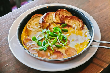 breakfast: fried eggs with croissants and sausage in pan