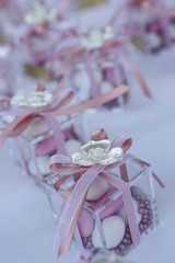Obraz na płótnie Canvas serie di bomboniere con confetti da matrimonio, dentro deliziose scatolette in vetro e fiocchi rosa
