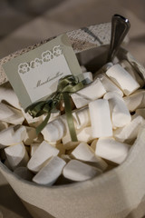 grippo di marshmallow bianchi dentro un contenitore in tessuto con cucchiaino e cartellino