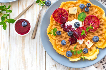 Fototapeta na wymiar Belgium waffles with blueberry, blood orange, whipped cream. Breakfast