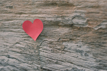 Red blank paper note with heart shape on grunge wooden background