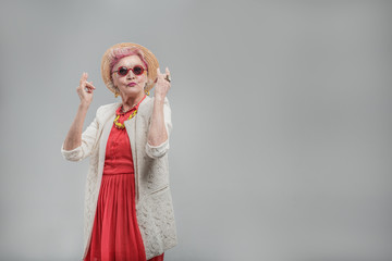 Cheerful aged woman in sunglasses enjoying music