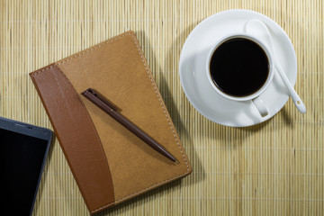 Hot coffee cup with notebook and mobile