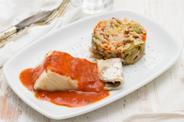 boiled cod fish with tomato sauce and rice on plate