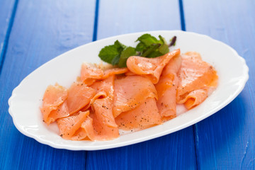 smoked salmon on white plate on wooden background