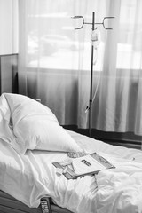 black and white photo of empty bed in hospital chamber