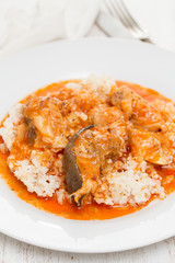 fish stew with rice on white plate on wooden background