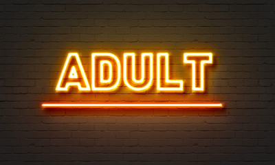 Adulte neon sign on brick wall background.