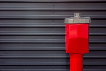 Roter Hydrant vor grauer Wellblechwand