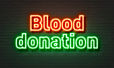 Blood donation neon sign on brick wall background.