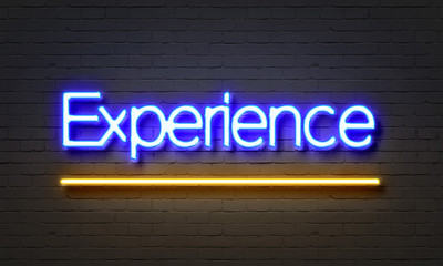 Experience neon sign on brick wall background.