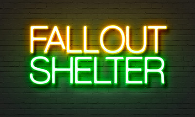 Fallout shelter neon sign on brick wall background.