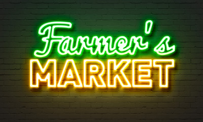 Farmers market neon sign on brick wall background.
