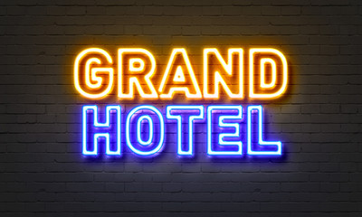 Grand hotel neon sign on brick wall background.