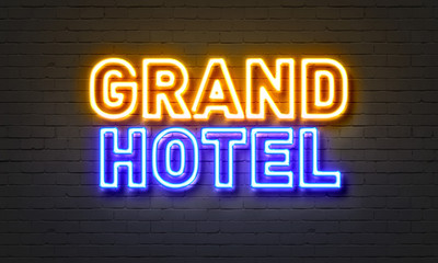 Obraz premium Neonowy znak Grand Hotel na tle ceglanego muru.