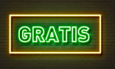 Gratis neon sign on brick wall background.