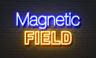 Magnetic field neon sign on brick wall background.