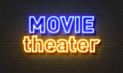 Movie theater neon sign on brick wall background.