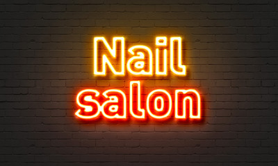 Nail salon neon sign on brick wall background.