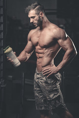 Fototapeta na wymiar Muscular Man Resting After Exercise And Drinking From Shaker
