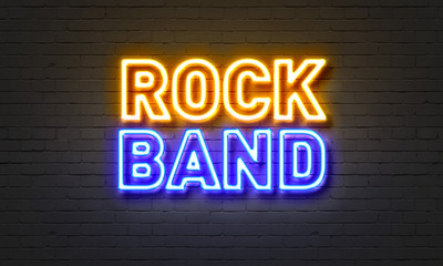 Rock band neon sign on brick wall background.