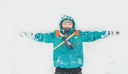 Happy boy lying on snow