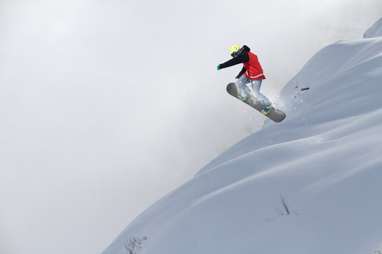 Flying snowboarder on mountains. Extreme winter sport.
