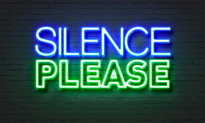 Silence please neon sign on brick wall background.
