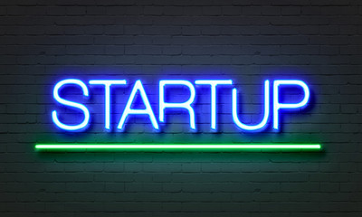 Obraz premium Startup neon sign on brick wall background.