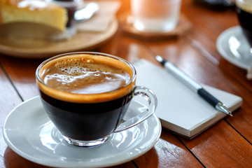 Coffee cup with blurred behind pen on  notebook.