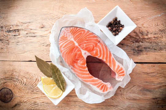 Raw salmon fish steak with lemon and spices on wooden rustic background. Fresh fish. Top view, copy space