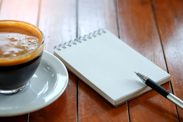 Pen on notebook with coffee cup.