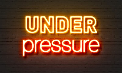 Obraz premium Under pressure neon sign on brick wall background.