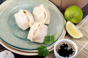 Uzbek dumplings (manti) with sauce and black chopsticks on glass plate