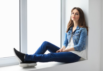 Young beautiful woman relaxing on window sill