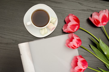 Coffee mug, marshmallow, clean sheet and pink tulips. Black table. top view