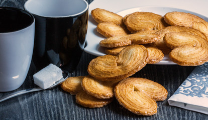 Gâteaux palmiers sur fond sombre avec tasse et sucre