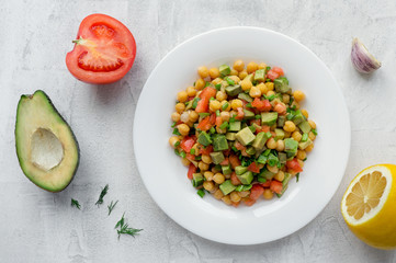 Chickpea diet salad with tomato, avocado and lemon juice on concrete table