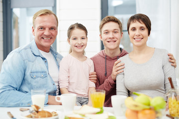 Four family mambers sitting by table with organic food